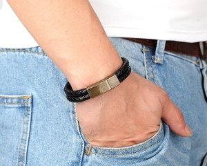 Detail of men's double braided black leather bracelet with vintage gold magnetic clasp