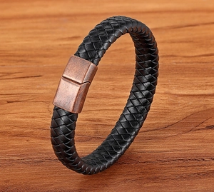 Macro detail of braided black leather bracelet with copper magnetic clasp on wood