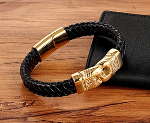 Close-up of black braided leather bracelet with gold engraved magnetic clasp on wood table