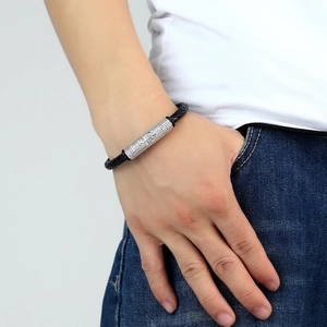 Close-up of black braided leather bracelet with crystal-encrusted silver metal cylinder bead