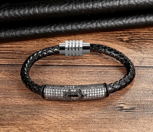 Close-up of black braided leather bracelet featuring a silver anchor charm and magnetic clasp