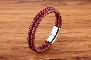 Close-up of red and black braided leather bracelet with silver magnetic buckle on wood