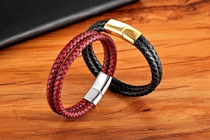Detailed view of woven leather bracelets with magnetic stainless steel clasps on wood