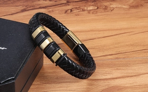 Detail of men's black braided leather bracelet with magnetic clasp and gold accents