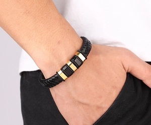 Detailed view of men's black braided leather bracelet with gold and black steel buckles