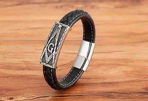 Detail eines schwarzen Lederarmbands mit Freimaurer-Kompass und Metallplakette