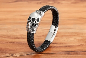 Detail of silver skull charm on braided black leather bracelet with magnetic clasp