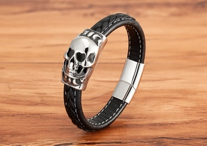 Detailansicht eines geflochtenen schwarzen Lederarmbands mit Totenkopf und Magnetverschluss
