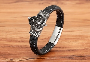 Nahaufnahme des silbernen Cobra-Anhängers auf schwarzem geflochtenem Lederarmband für Herren