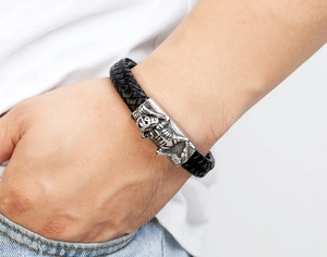 Close-up of men's braided black leather bracelet with silver skull metal magnetic clasp
