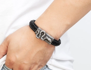 Nahaufnahme eines Herren-Lederarmbands mit silbernem Schlangen-Metallanhänger