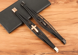 Detail van meerlaagse gevlochten lederen armbanden met metalen kruis en magneetsluiting