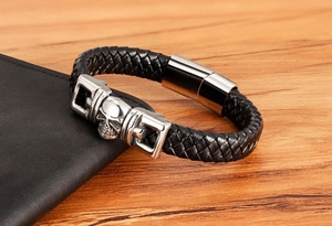 Detailed close-up of men's black braided leather bracelet with silver skull charm