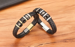 Detail shot of woven black leather bracelets with polished gold and silver metal charms