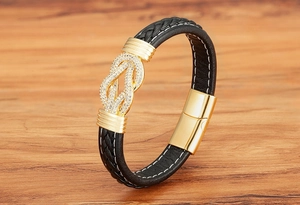 Detail eines geflochtenen Lederarmbands mit vergoldetem Knoten und Zirkonia-Akzenten
