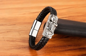 Close-up of men's braided leather bracelet featuring a silver skull magnetic clasp