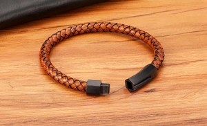 Detailed close-up of brown braided leather bracelet with black matte magnetic buckle on wood