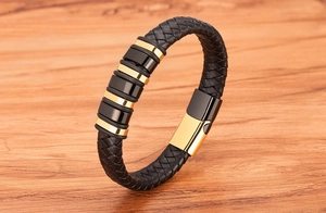 Detail of black braided leather men's bracelet with gold polished metal rings and clasp