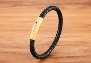 Detail of woven black leather bracelet with a polished gold magnetic metal clasp
