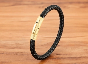 Gros plan d'un bracelet en cuir tressé noir avec fermoir en métal doré sur bois