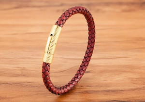 Détail d'un bracelet en cuir tressé brun rouge avec fermoir magnétique doré texturé