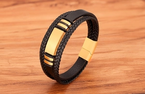 Detail eines mehrlagigen schwarzen Lederarmbands mit goldenem Magnetverschluss auf Holz
