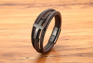 Macro-opname van een meerlaagse donkerbruine leren armband met een donkergrijze metalen kruis