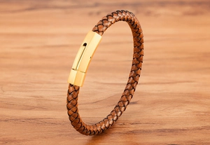 Detailed close-up of brown braided leather strap with a polished gold cylindrical clasp