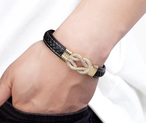 Makroaufnahme von schwarzem Lederarmband mit Goldknoten und Pavé-Kristallen