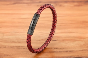 Gros plan détaillé d'un bracelet en cuir tressé rouge avec fermoir texturé noir fusil
