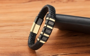 Detail of woven black leather bracelet with polished black and gold stainless steel buckle