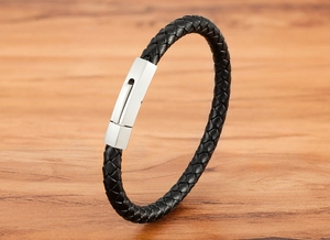 Detailed macro view of woven black leather strap and brushed stainless steel clasp