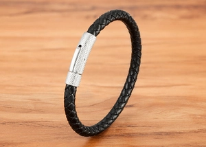 Détail d'un bracelet en cuir tressé noir avec un fermoir en métal argenté à texture diamant