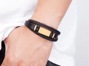 Detail eines mehrlagigen Herren-Lederarmbands mit polierter Gold-Metallplatte am Handgelenk