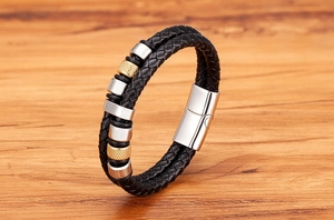 Detail eines schwarzen Lederarmbands mit Gold- und Silberperlen auf Holzoberfläche