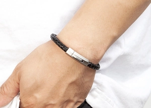 Detailed close-up of handmade black braided leather bracelet with silver matte buckle on wrist