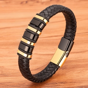 Men's braided black leather bracelet with gold metal charms on natural wood surface