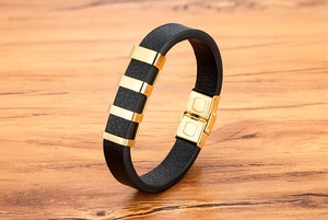 Dettaglio di un bracciale in pelle nera da uomo con perle in acciaio inossidabile oro