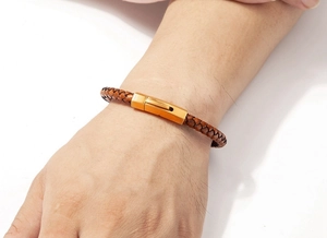 Close-up of braided dark brown leather bracelet with golden clasp on a male wrist