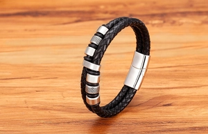 Detailansicht des schwarzen Lederarmbands mit silbernen Perlen auf Holzuntergrund