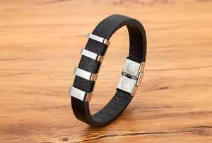 Dettaglio macro del bracciale in pelle nera da uomo con barre decorative in acciaio lucido