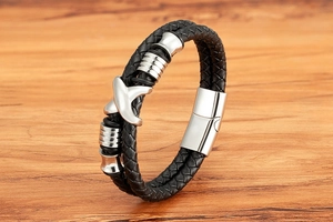 Nahaufnahme Herren Lederarmband geflochten schwarz mit silbernem X-Anhänger und Magnetverschluss