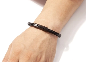 Close-up of black braided leather bracelet with matte black metal clasp on male wrist