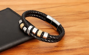 Detail eines geflochtenen schwarzen Herren-Lederarmbands mit gold gerändelten Metallteilen