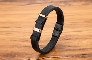 Dettaglio bracciale uomo in pelle con chiusura in acciaio inox su tavolo di legno