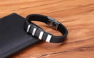 Dettaglio macro del bracciale da uomo in pelle nera con barre in acciaio su legno