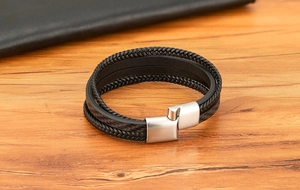 Détail d'un bracelet multicouche en cuir noir avec un fermoir magnétique en métal argenté