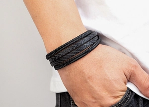 Gros plan d'un bracelet multicouche en cuir noir pour homme avec corde tressée et texture carbone
