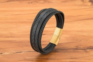 Détail d'un bracelet multicouche en cuir noir avec sangle texturée et fermoir magnétique doré