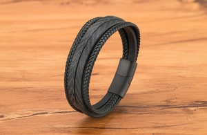 Détail d'un bracelet multicouche en cuir noir avec fermoir magnétique sur fond de bois